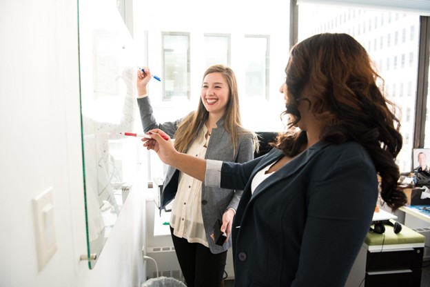 Two ladies working on a white board